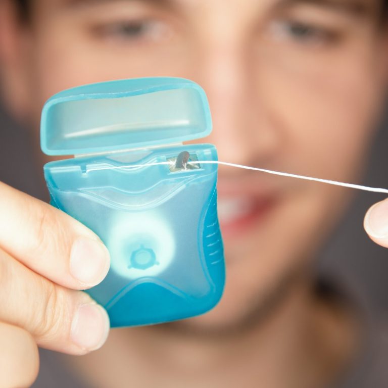 A male pulling floss out of box ready to use and get stucked food out of teeth